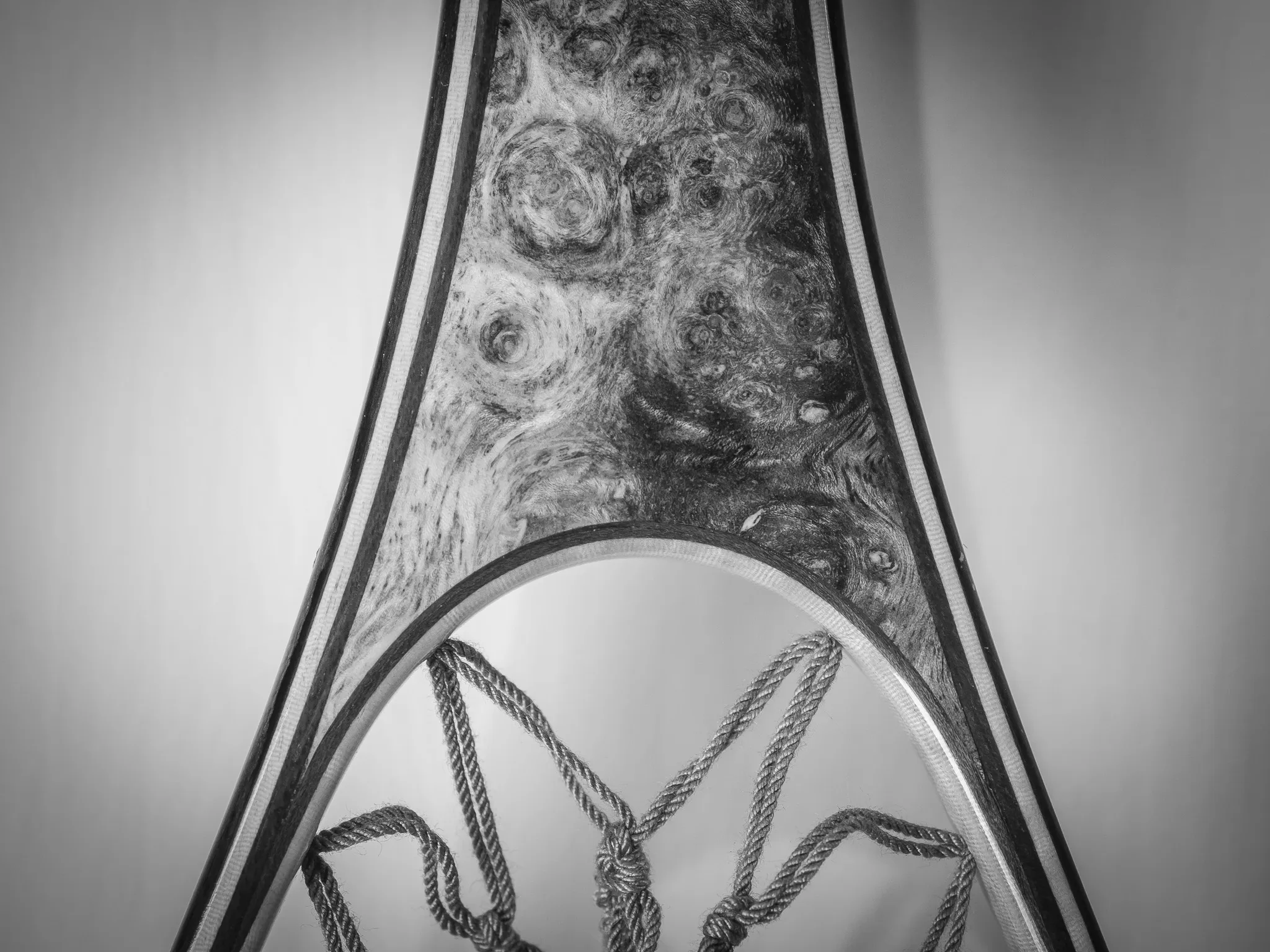 Black and white detail of a landing net frame in burl wood with cord